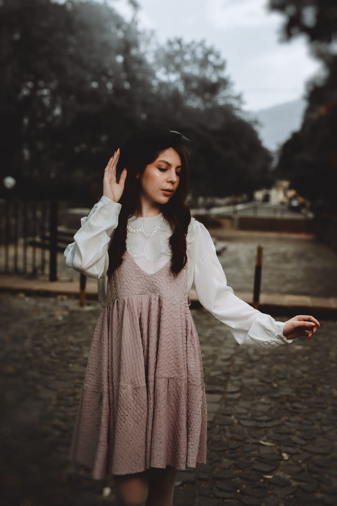 Woman in a mauve dress layered over a white blouse in a park