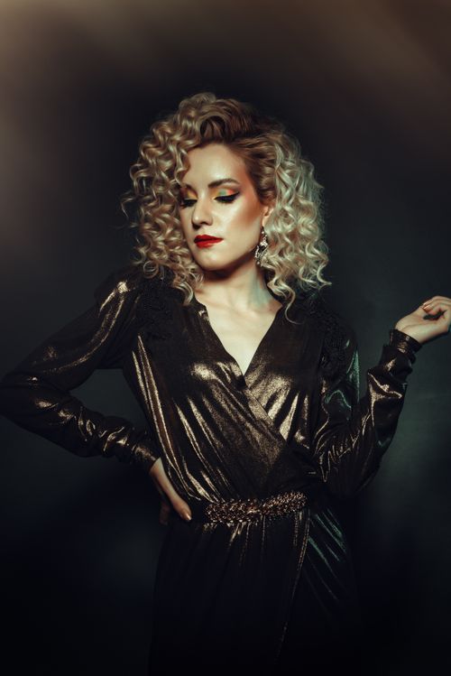 Free Striking portrait of a glamorous woman with blonde curls in a metallic dress, exuding elegance. Stock Photo