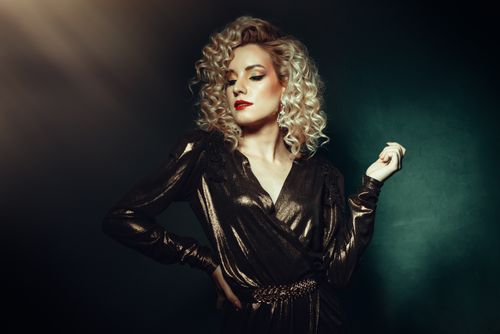 Free Glamorous blonde woman posing confidently in elegant evening wear with dramatic lighting. Stock Photo