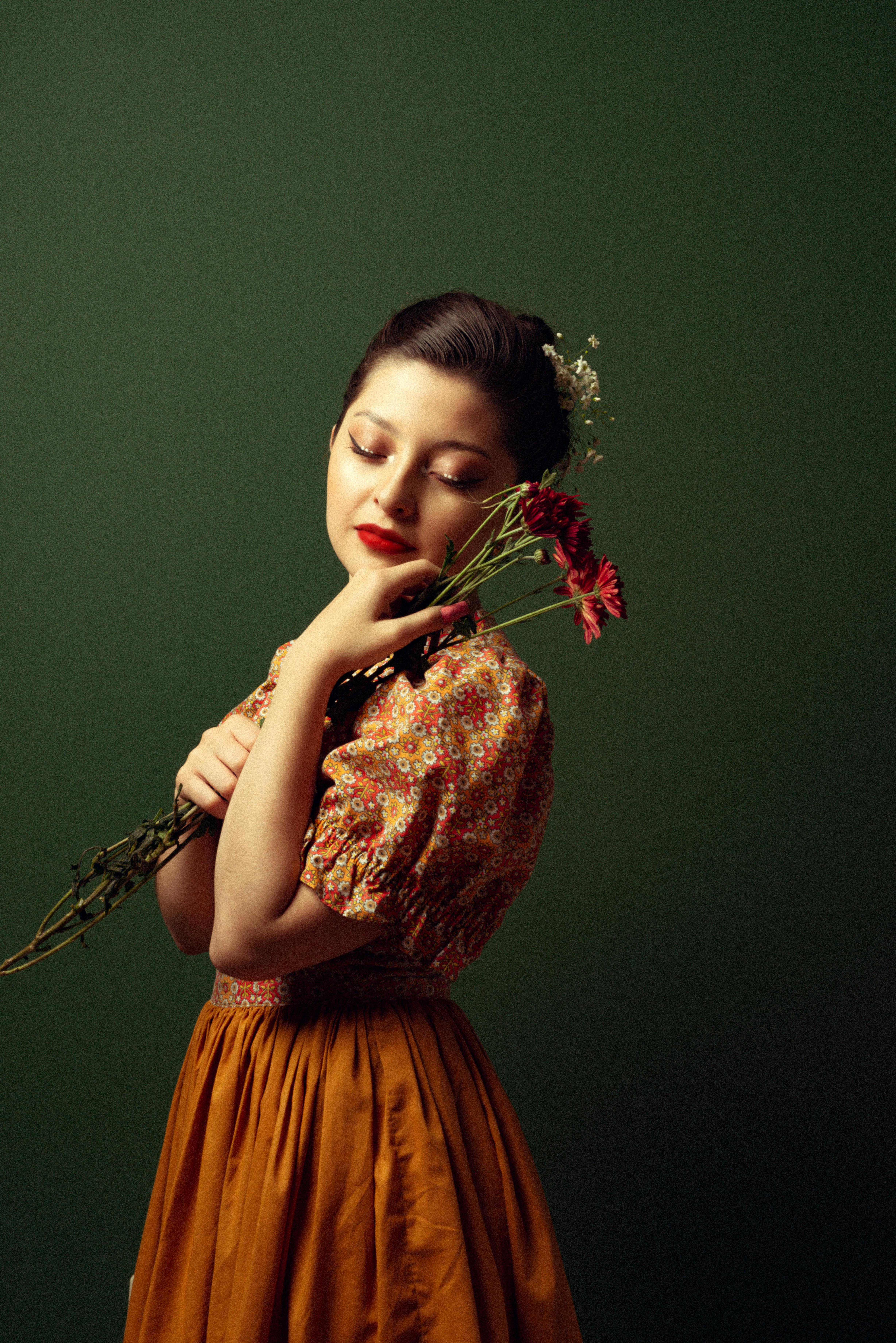 A serene woman with closed eyes and a bouquet, showcasing elegance against a green background.