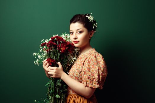 A captivating portrait of a woman holding a vibrant bouquet against a green backdrop.