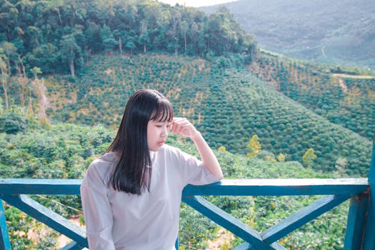一位年轻女子若有所思地站在阳台上，俯瞰着郁郁葱葱的青山
