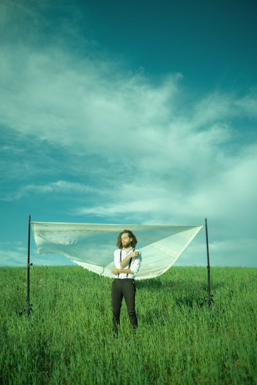 Man Standing in the Pasture in Front of a Hanging White Sheet 