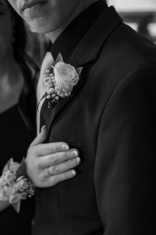 Free Close-up of a man's suit with a rose boutonniere and a woman's hand in black and white. Stock Photo