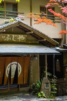 Charming facade of a traditional Japanese ryokan with autumn leaves in Kyoto, Japan.
