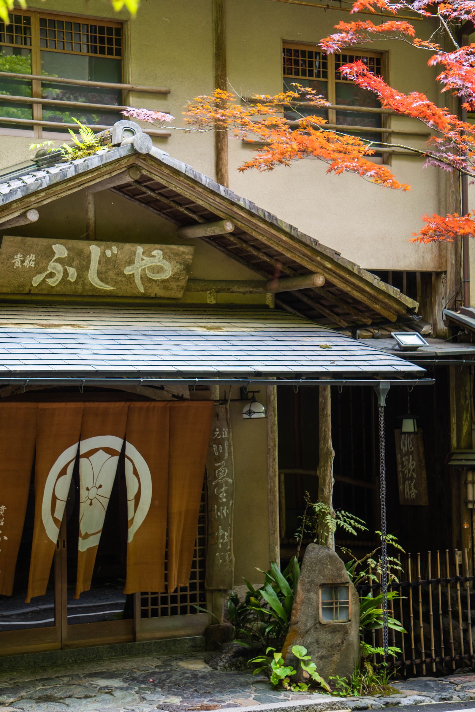 Traditional ryokan facade with autumn maple leaves in Japan