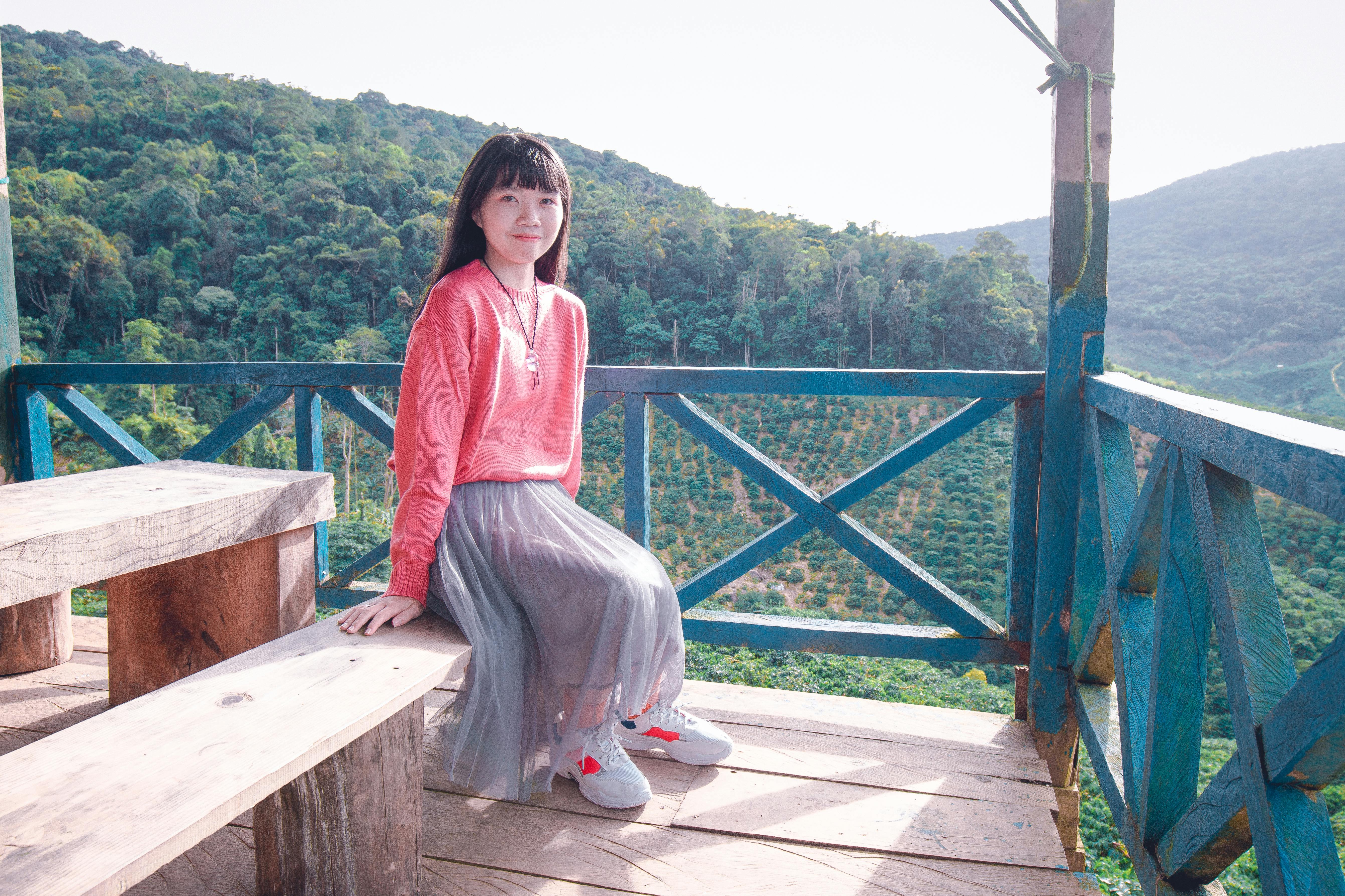亚洲妇女在木阳台上享受宁静时刻，可以欣赏风景优美的山景