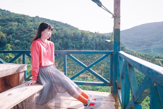 一位穿着粉色毛衣的年轻女子，在风景优美的山脉背景的木阳台上放松身心