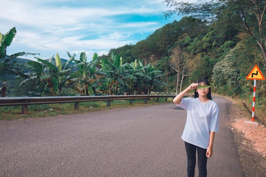 一名年轻女子顽皮地站在一条热带树叶繁茂、风景优美的道路上