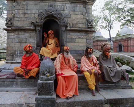 Five sadhus sit by a temple in Pashupatinath, Kathmandu, showcasing Hindu culture and spirituality.