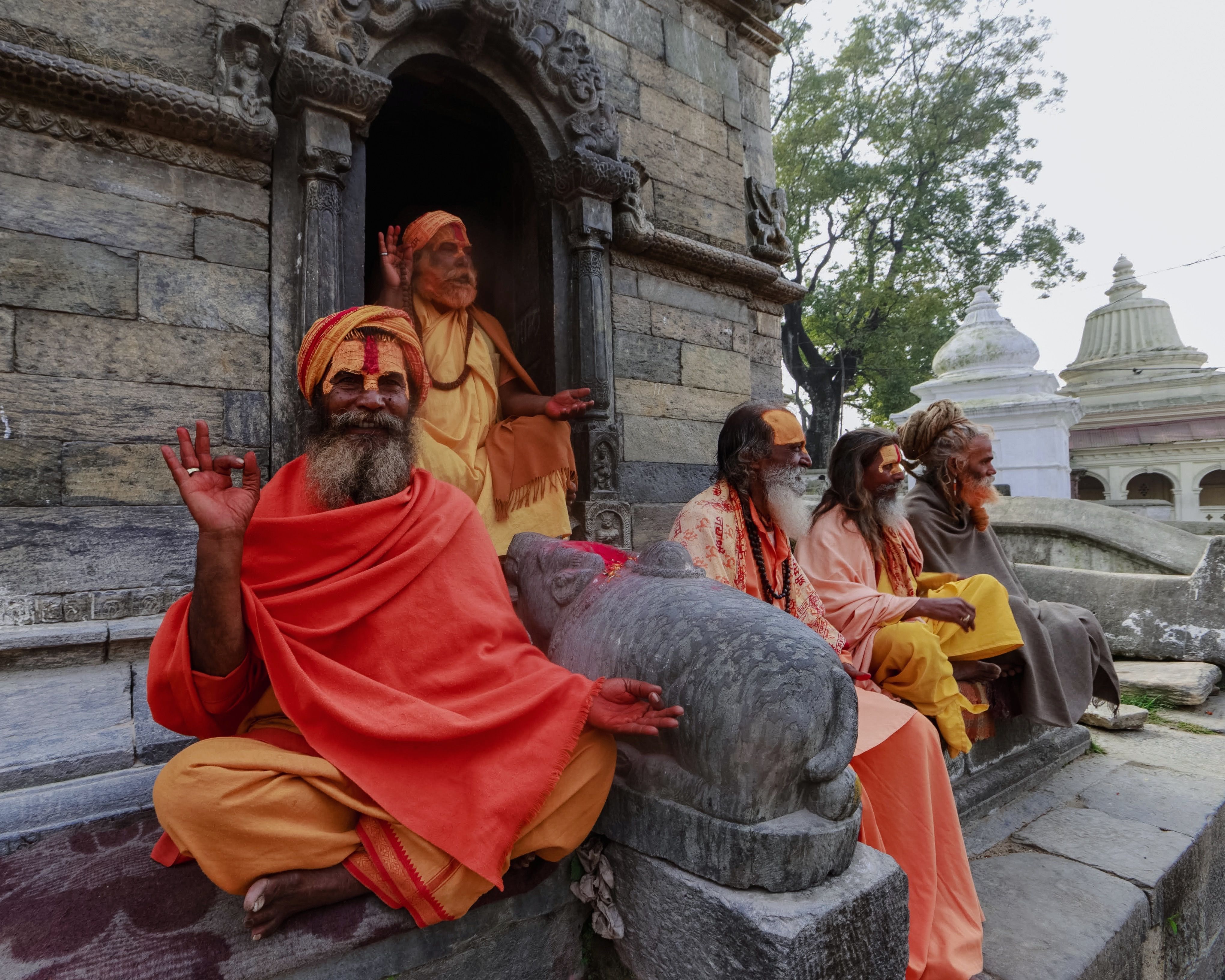 Group of Sadhu monks in traditional robes meditating at an ancient Hindu temple.