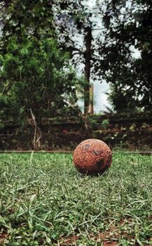A worn soccer ball on a grass field, showcasing rustic texture and natural surroundings.