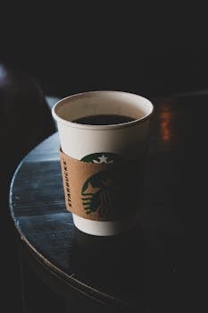 Close-up of a coffee cup on a dark table, moody lighting enhances the café ambience.