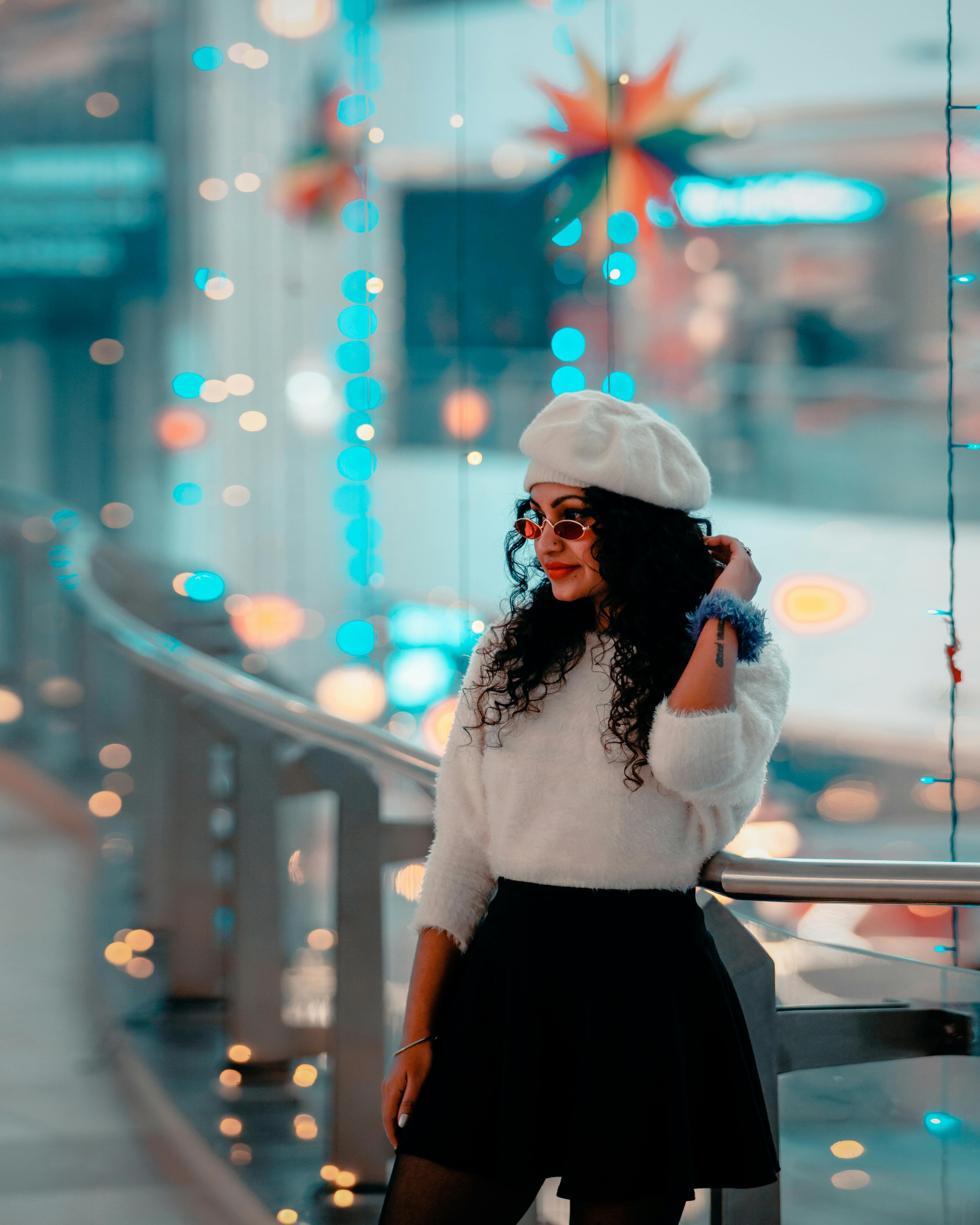 Stylish woman in a beret, surrounded by vibrant lights and festive decor in an indoor setting.