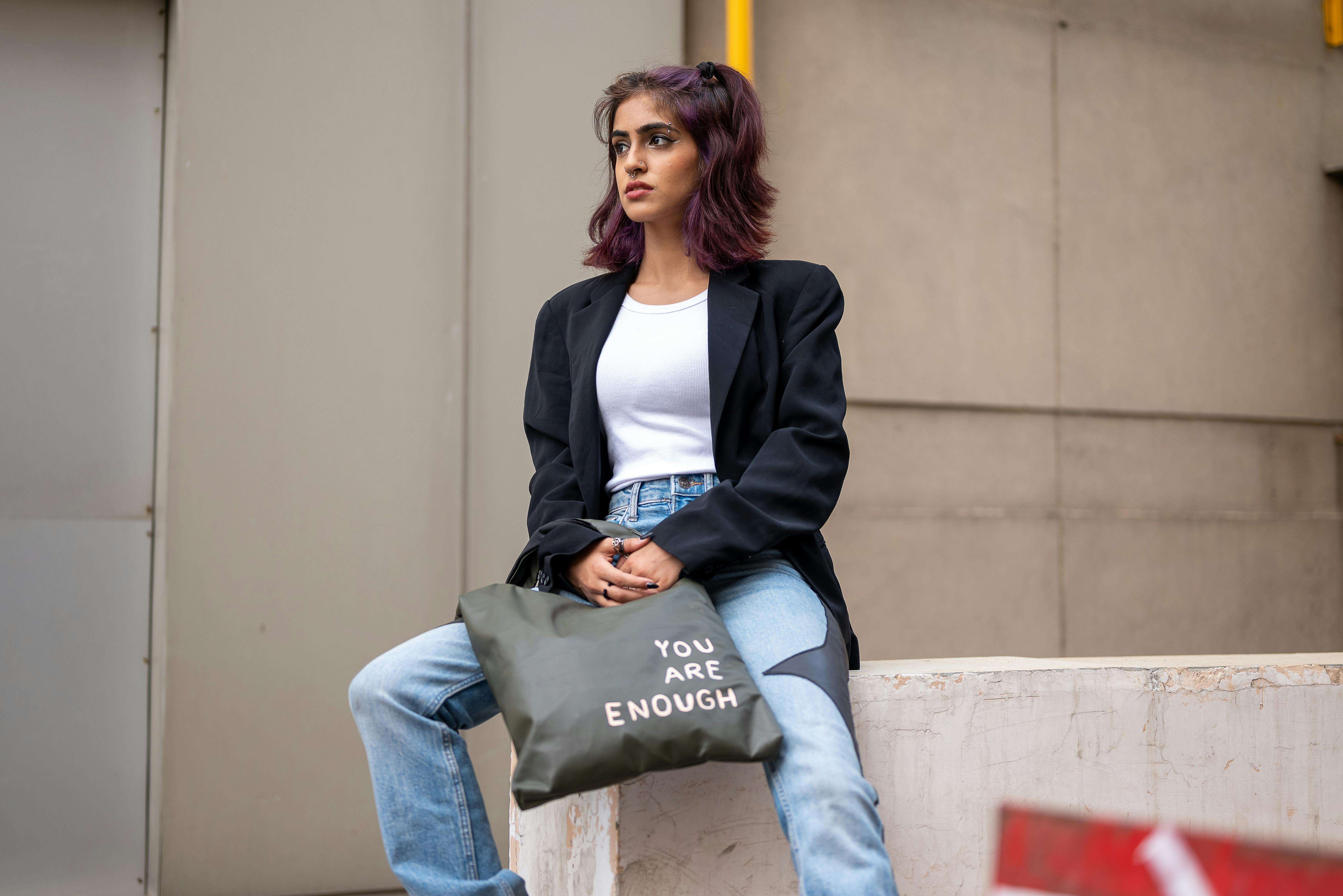 Gen Z woman wearing a minimalist beige trench coat, no logos, holding a leather tote bag in a city street
