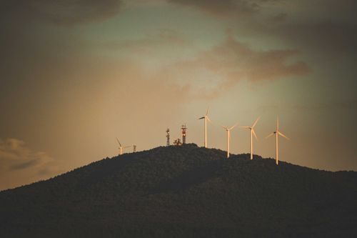 Free Wind turbines on a hilltop during dusk. Stunning view highlighting renewable energy. Stock Photo