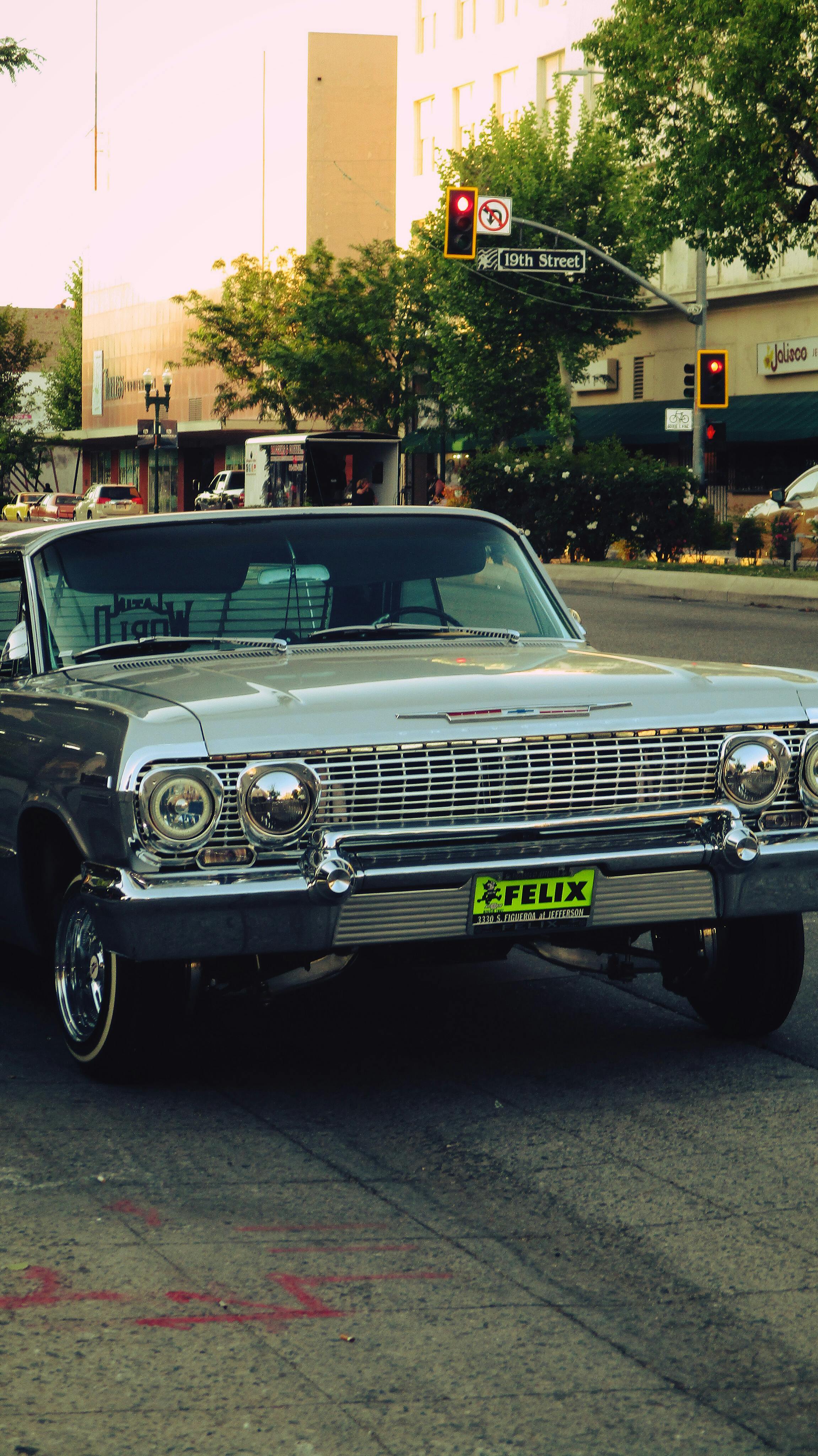 Classic Chevrolet Impala cruising through urban streets, showcasing vintage automotive design.