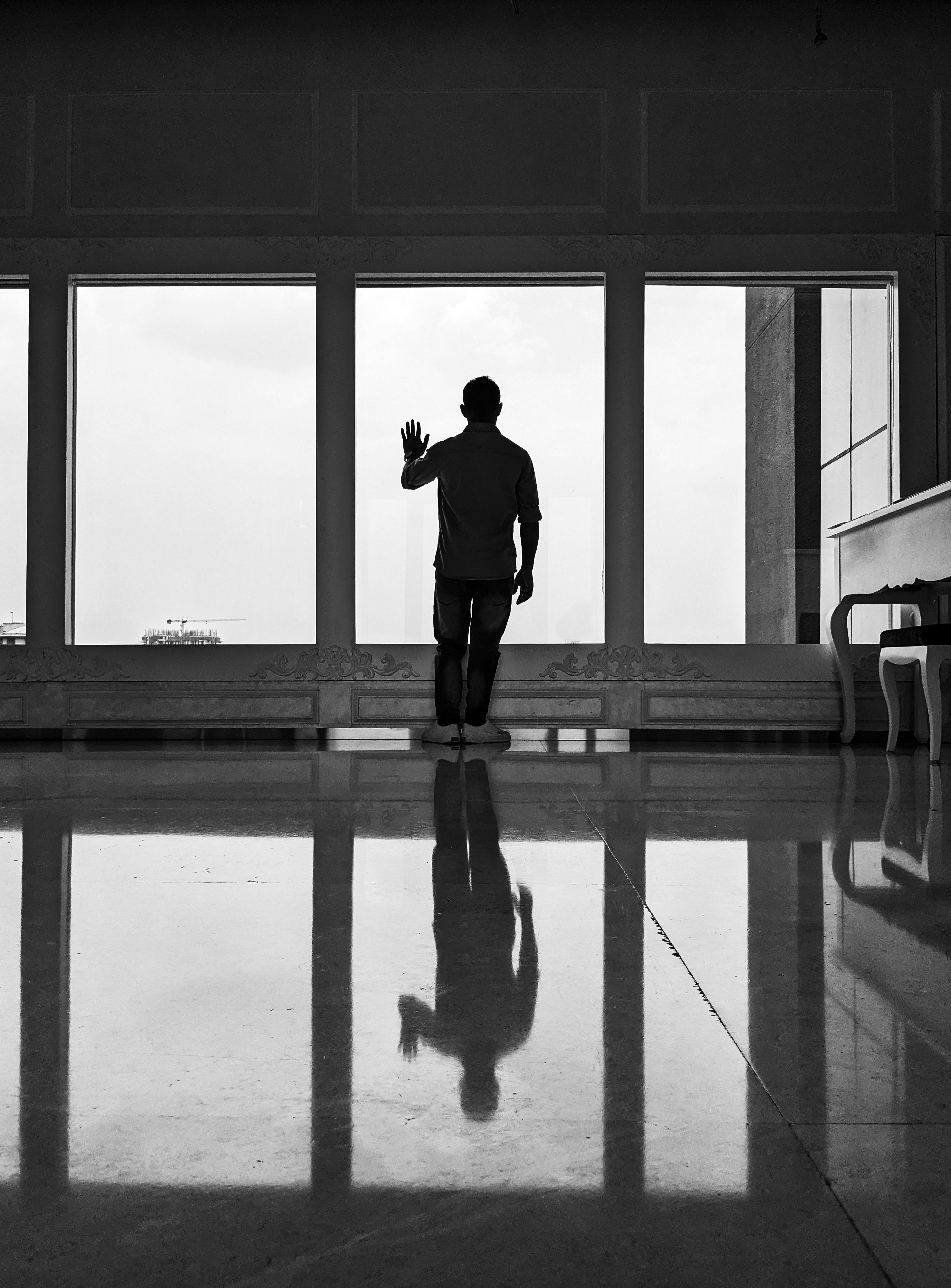 Grayscale photo of man standing near window photo – Free Cloud