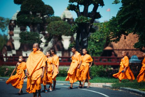 Free Group of Theravada Buddhist monks in saffron robes walking outside a temple on a sunny day. Stock Photo