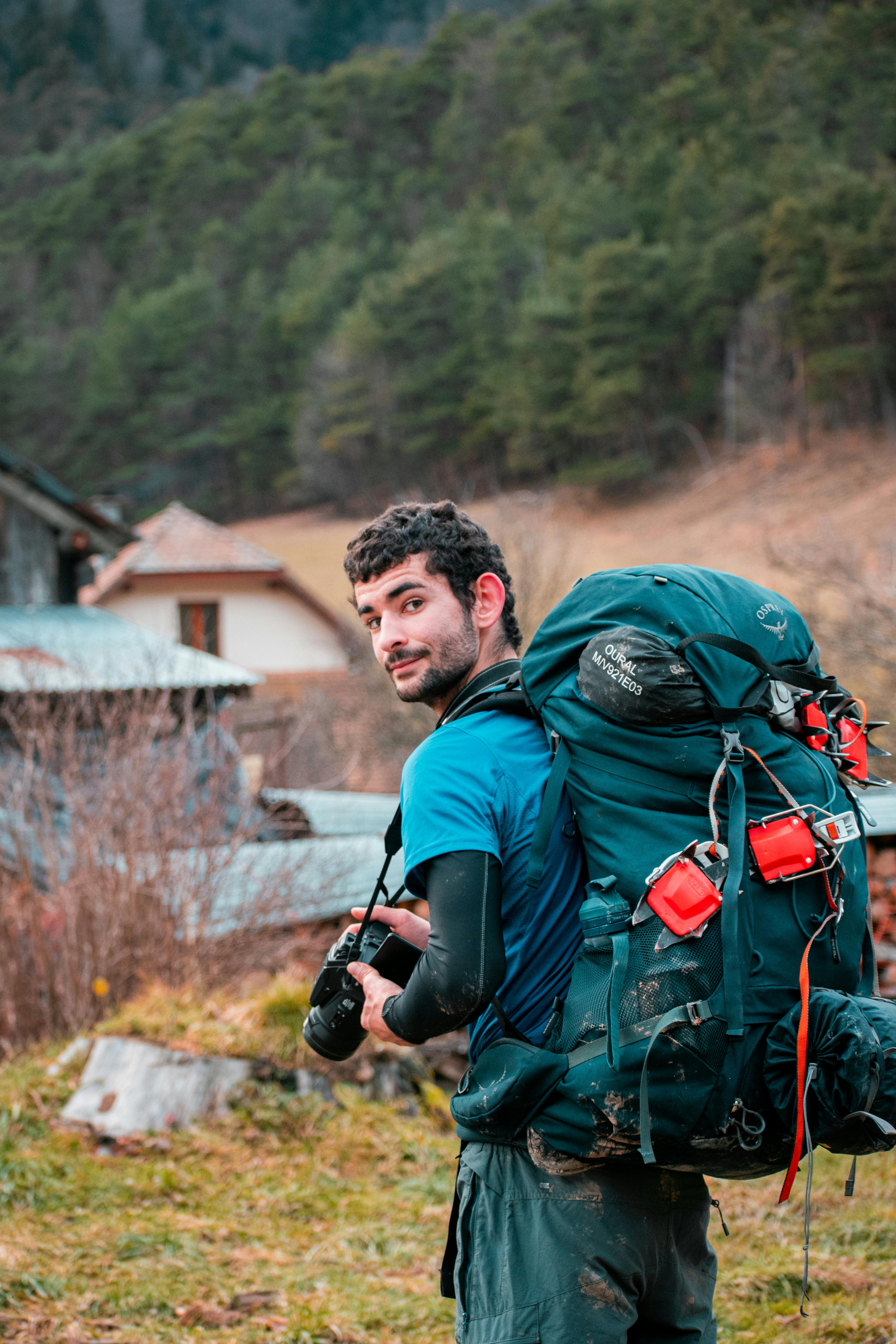 A backpacker holding a camera explores Saint-Martin-de-Clelles, France, surrounded by nature.