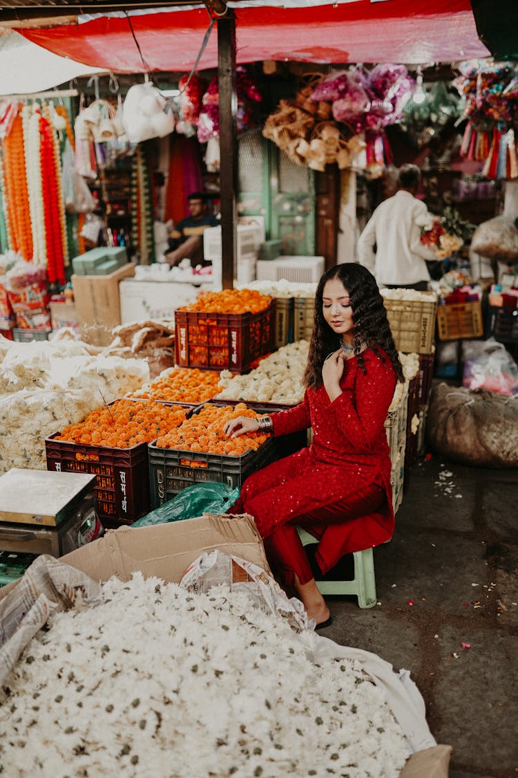 Woman Sitting On Bazaar And Posing Among Fruit And Vegetables