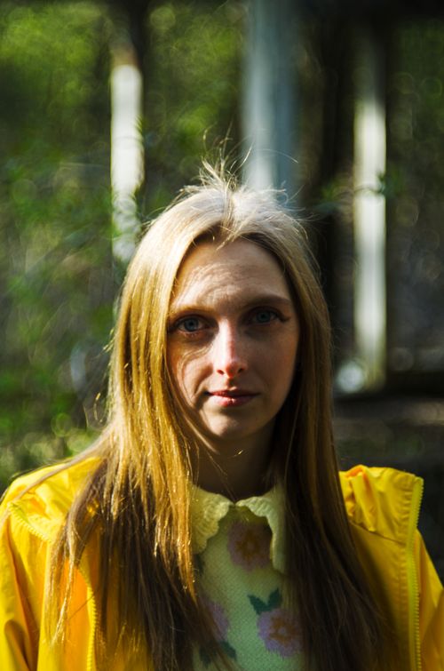 Free Portrait of a young woman wearing a yellow raincoat posing in a forest. Fashion and nature blend. Stock Photo