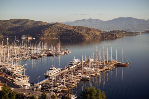 Free Aerial view of a marina with sailboats and yachts on a serene bay surrounded by mountains. Stock Photo