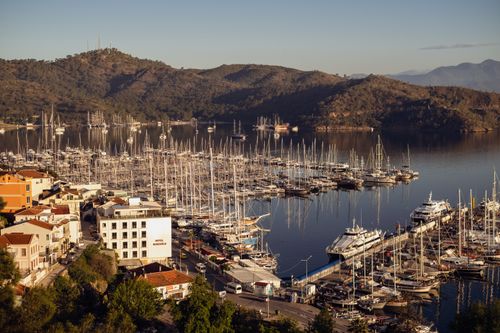 Free Aerial shot of Fethiye marina with moored sailboats and picturesque mountains at sunset. Stock Photo