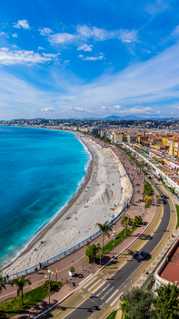 Stunning aerial view of the Promenade des Anglais and beach in Nice, France under a bright blue sky.