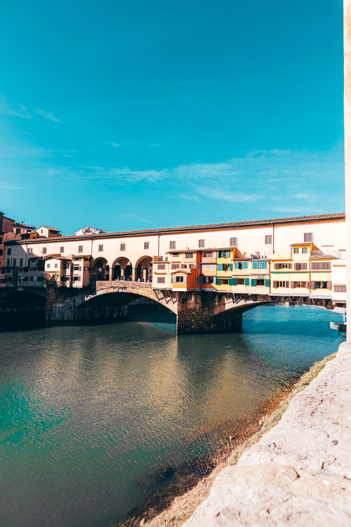 Free Beautiful view of Ponte Vecchio spanning the Arno River in Florence, Italy, under a clear summer sky. Stock Photo
