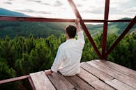 一个人从木制观景台俯瞰郁郁葱葱的森林，享受着宁静的时刻