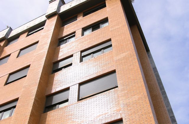 Low angle shot of a modern apartment building facade under clear skies in Oviedo, Spain.
