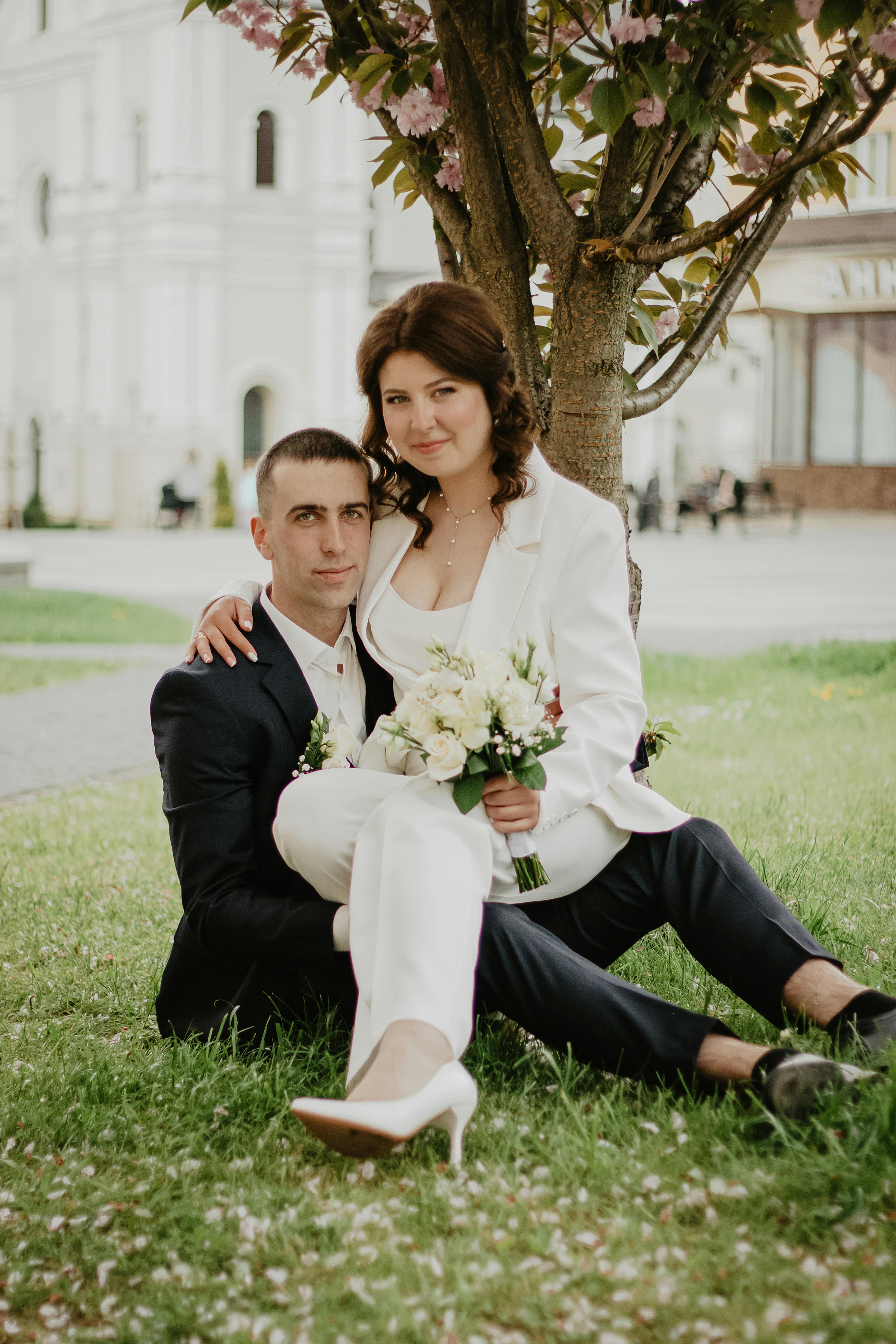 Newlyweds pose under a tree, sharing an intimate moment after their wedding ceremony.
