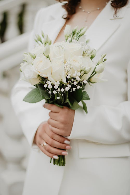 Close up of Bouquet in Hands of Woman in White Suit