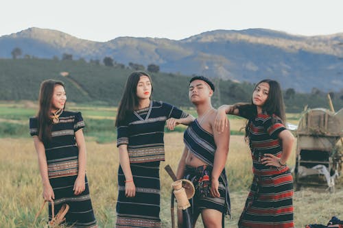 Three Women and One Man Standing Near Rice Paddy