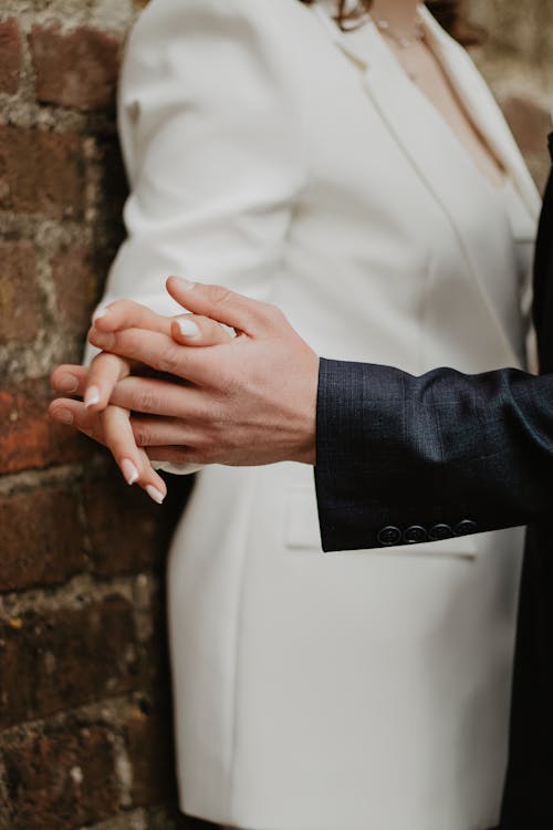 Newlyweds Holding Hands by the Brick Wall