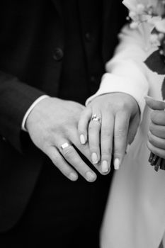 A black and white close-up of a couple's hands with wedding rings, symbolizing love and commitment.