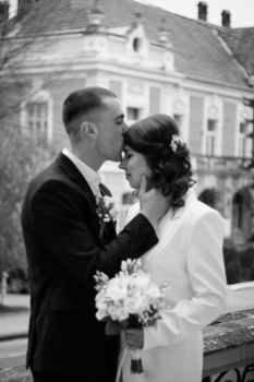 A classic black and white photo of a newlywed couple in a loving embrace outdoors.