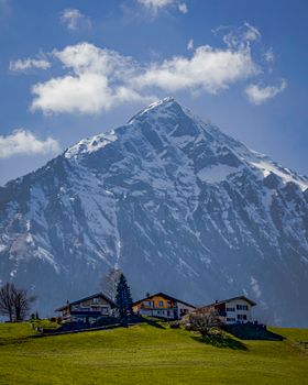 Picturesque view of snow-capped mountains and rural homes under a clear blue sky.