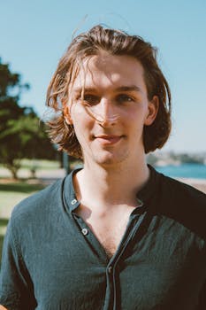 夏日阳光明媚，一个年轻人表情轻松地站在户外