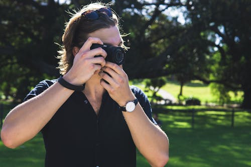 Homem Em Pé Segurando A Câmera E Tirando Fotos