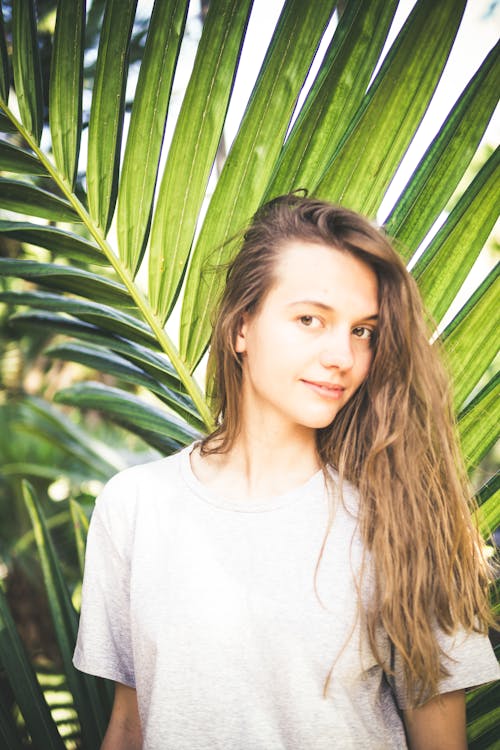 Photo of Woman Standing In Front of Palm Leaves