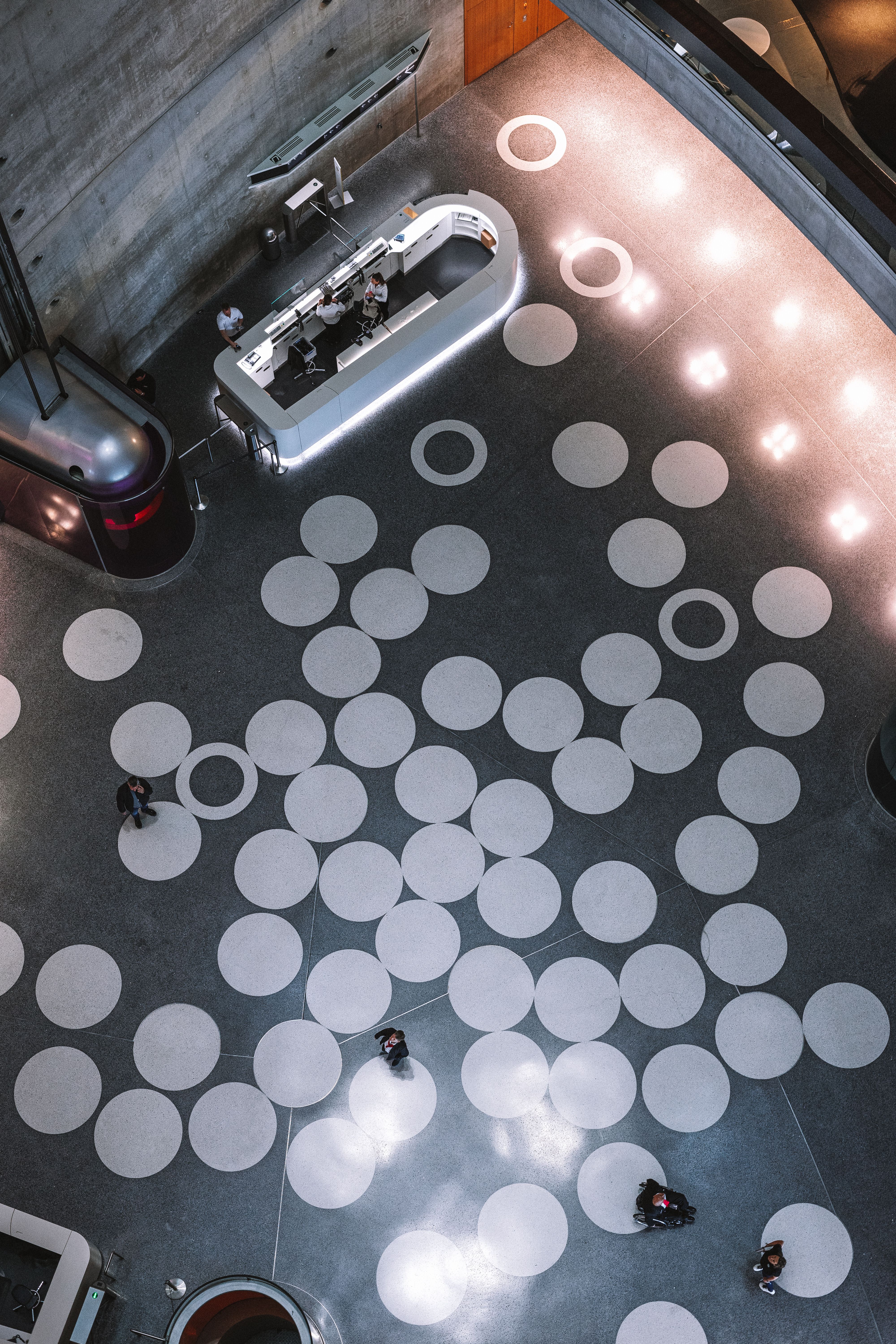 A futuristic lobby interior with a unique circular pattern and people walking.