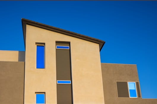 Modern residential building facade against a vivid blue sky, showcasing geometric windows.