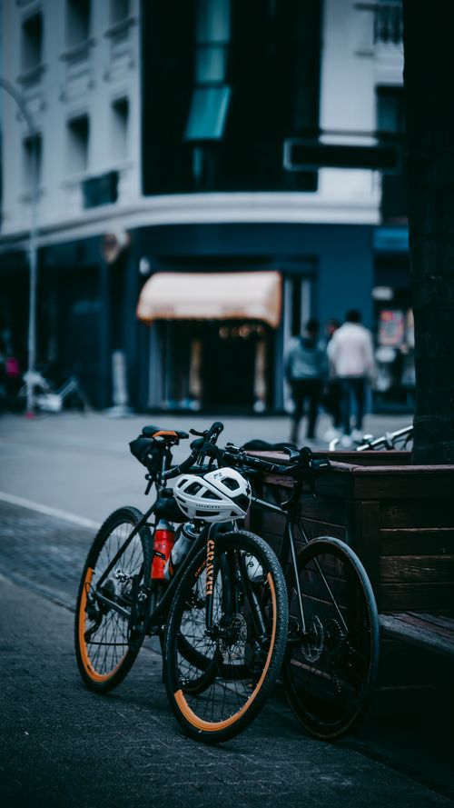 Free Bicycles parked on a city street with a blurred urban backdrop, suggesting a bustling atmosphere. Stock Photo