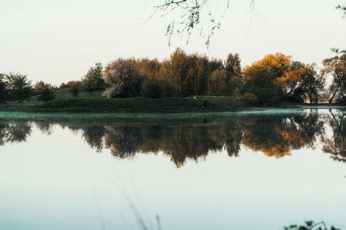 Free A tranquil autumn scene with trees reflecting in a still lake in Liepāja, Latvia. Stock Photo