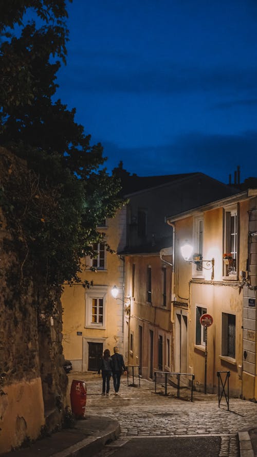 People on Cobblestone Street in Town at Night