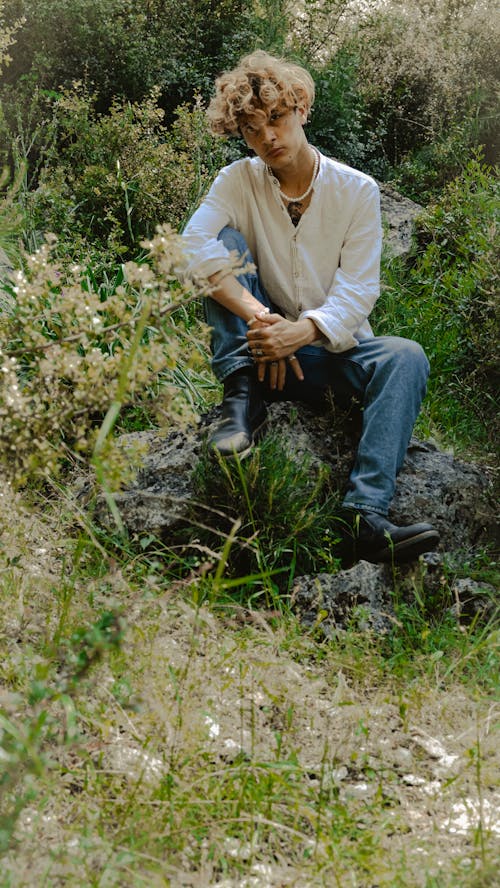 Free Young Man Sitting on the Rock on a Field  Stock Photo