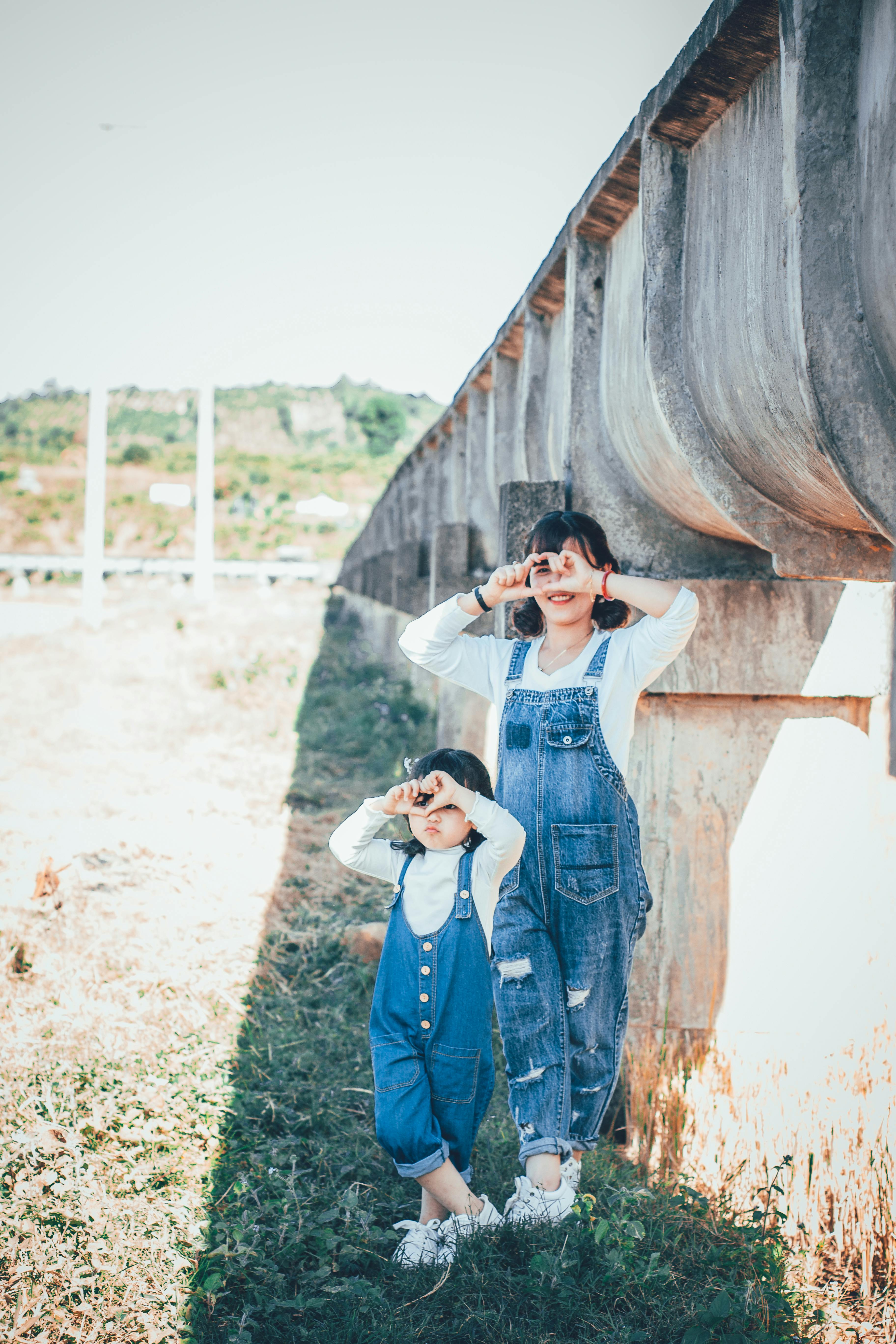 Two Girls Standing Beside Concrete Wall