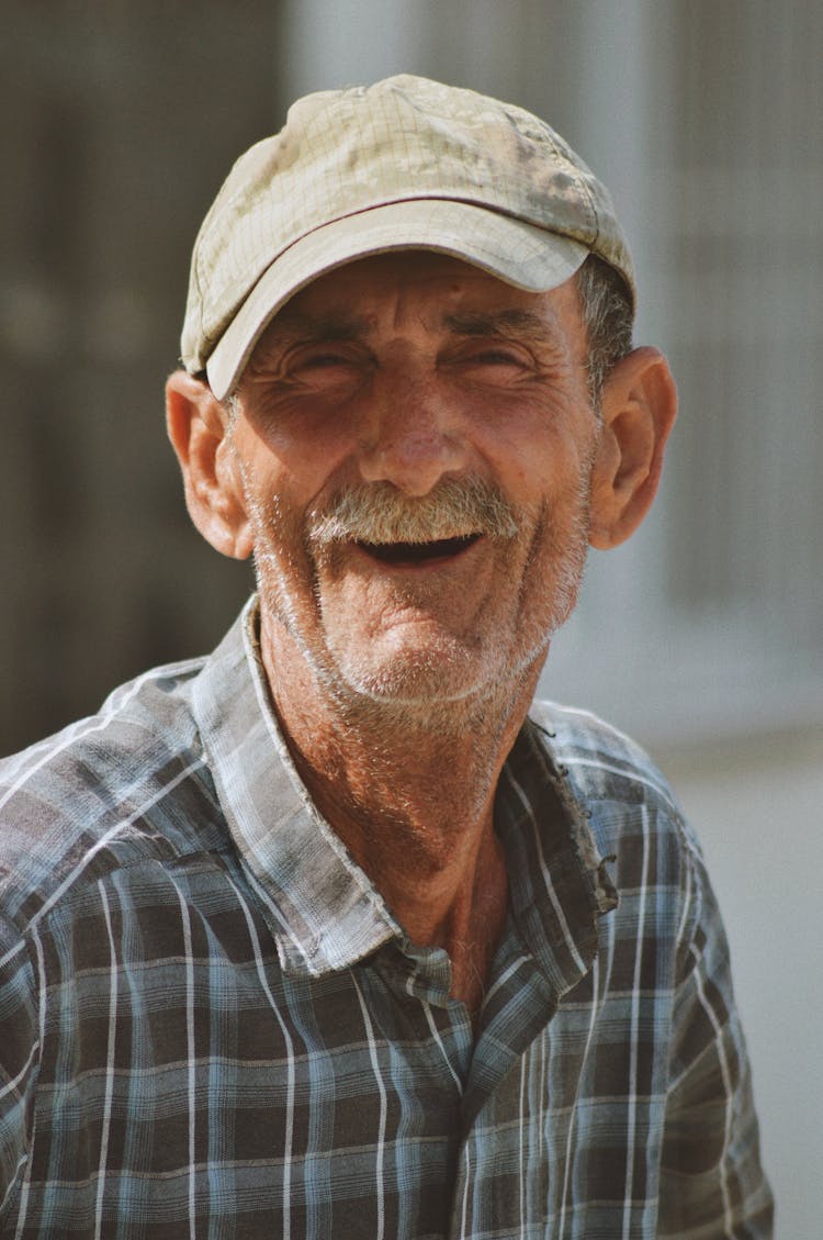 Portrait Of A Smiling Elderly Man Sitting Outside In Sunlight 